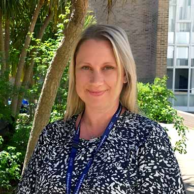 Emma Vaughan-Ginns Emma Vaughan-Ginns HE Walfare officer standing outside with trees and bushes behind her.